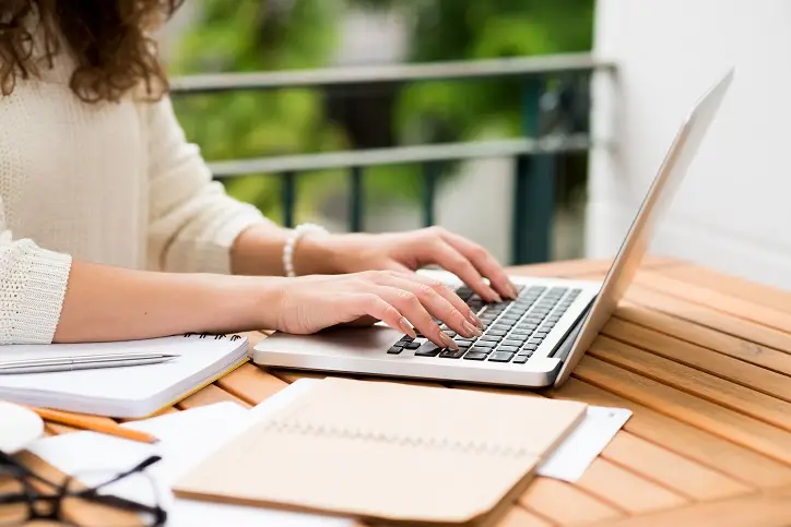Text wird von Frau auf Notebook getippt